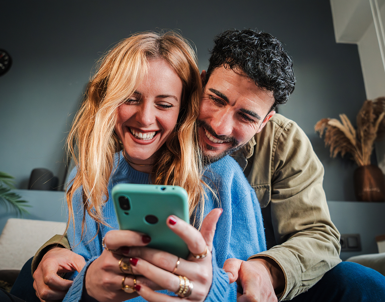 Coppia sorridente che consulta servizi e vantaggi di DRIV& sullo smartphone.