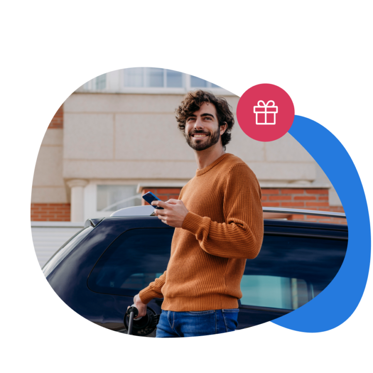 Ragazzo sorridente che consulta DRIV& sul suo smartphone mentre fa rifornimento.