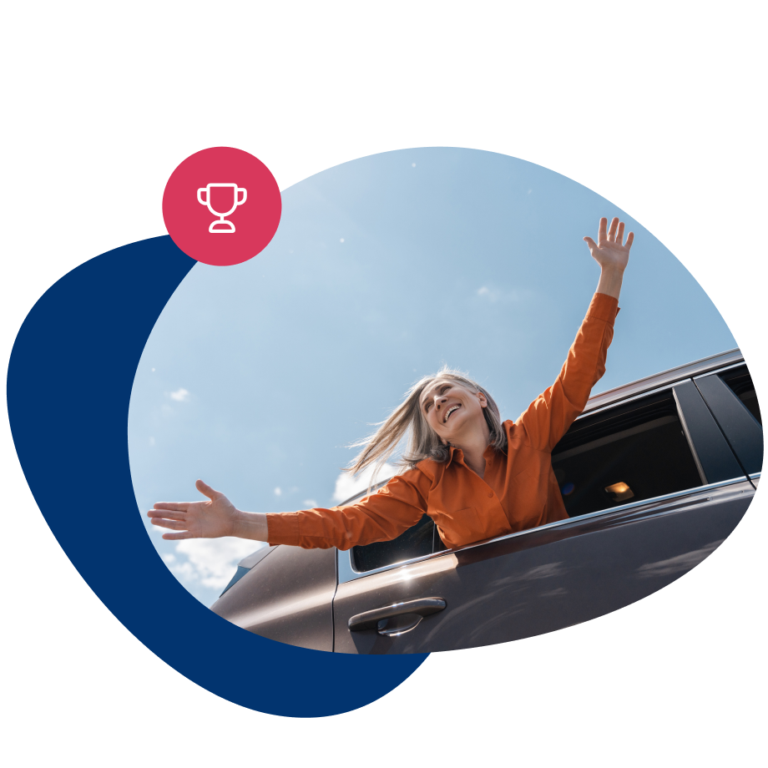 Donna sorridente che sporge dal finestrino dell’auto con le braccia aperte.